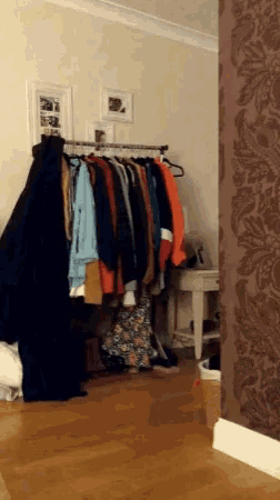 a bunch of clothes hanging on a rack in a closet
