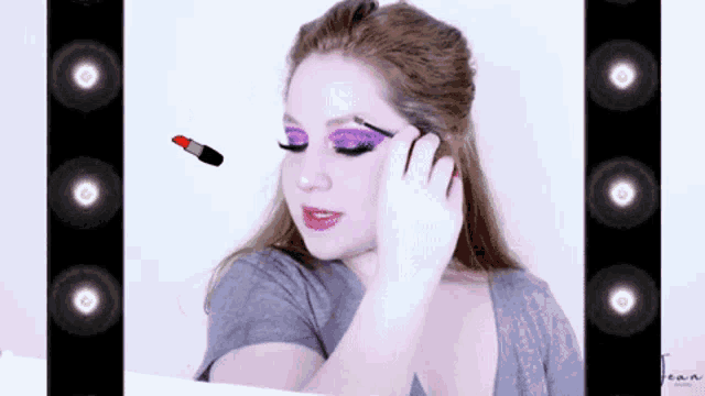 a woman is applying makeup in front of a mirror with a red lipstick flying in the air .
