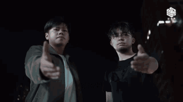 two men are standing next to each other and one of them is pointing at the camera