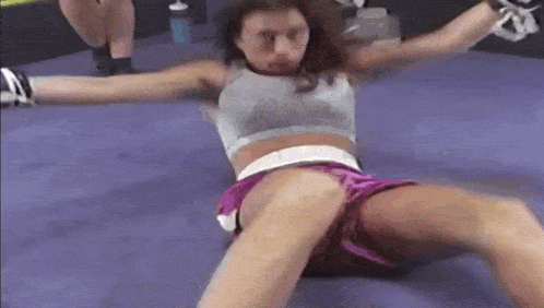 a woman is laying on the floor in a boxing ring with her legs crossed .
