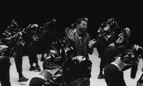 a man is standing in front of a group of people dancing .