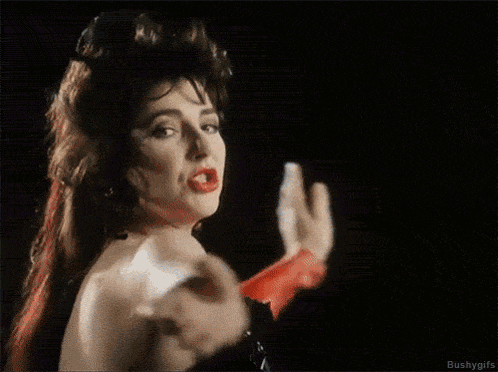 a woman in a black dress and red gloves is dancing in the dark