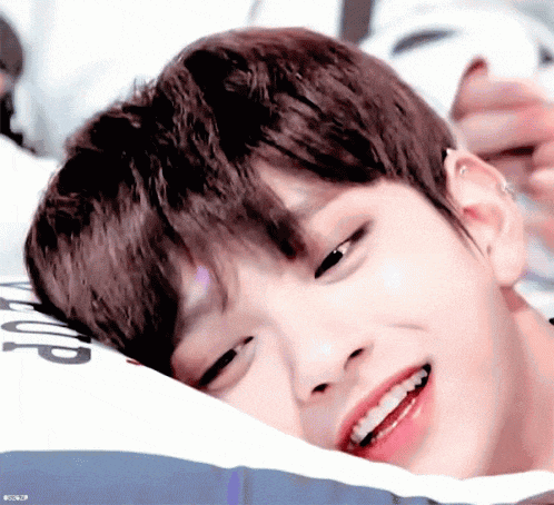 a close up of a person laying on a pillow with their eyes closed and smiling .