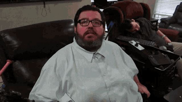 a man with glasses and a beard sits on a couch