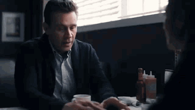 a man and a woman are sitting at a table in a diner talking to each other .