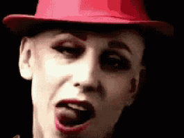 a woman wearing a red hat is sticking her tongue out