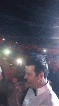 a man in a white shirt is smiling in a crowd