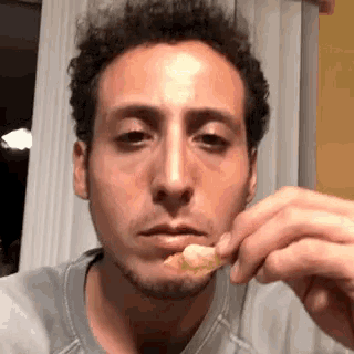 a man with a beard is eating a piece of food