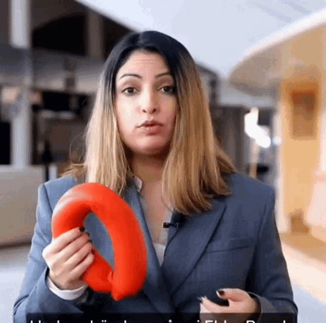 a woman in a suit is holding an orange object in her hands