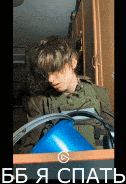 a man in a military uniform is sleeping on a desk with a blue bucket