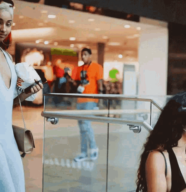 a woman in a white dress is standing next to a glass railing