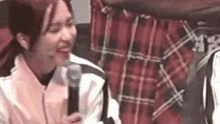 a woman is holding a microphone and smiling while sitting next to a man .