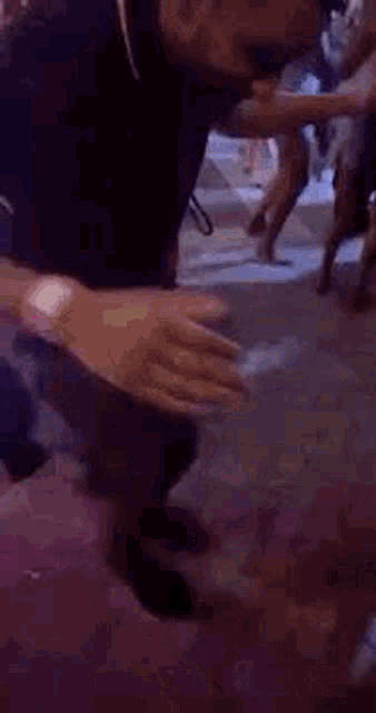 a man in a black shirt is kneeling down in a crowded room .