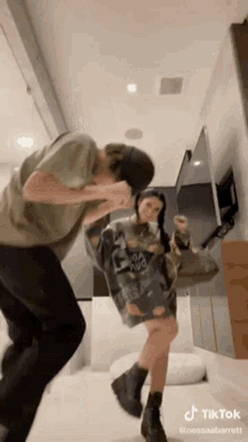 a man and a woman are dancing in a room with a tiktok watermark .