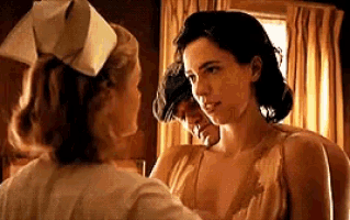 a woman in a nurse 's hat is touching a woman 's chest .