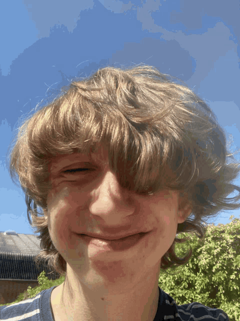 a young boy with a striped shirt on makes a funny face
