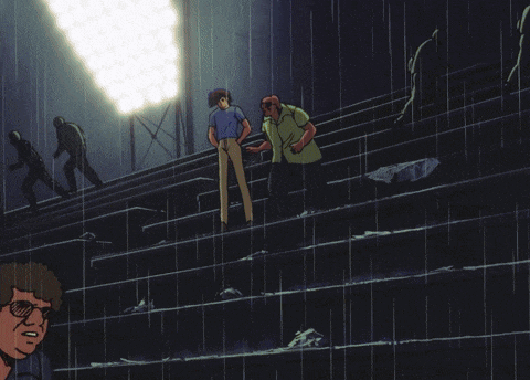a group of people standing in a stadium in the rain with one man holding his arm up