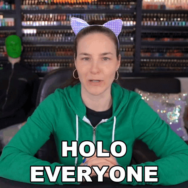 a woman wearing cat ears and a green hoodie says holo everyone