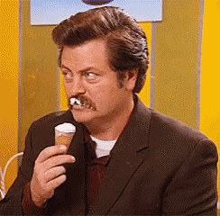 a man with a mustache is eating an ice cream cone .