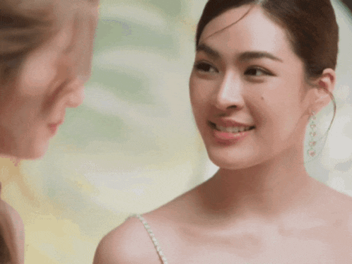 a woman in a white dress looks at another woman