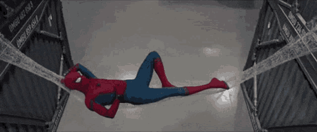 a man in a spiderman costume is laying on the floor with a spider web around him .