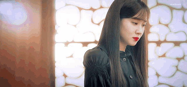 a woman with long hair and red lips is standing in front of a wall .