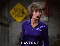 a woman in a purple shirt is standing in front of a sign that says laverne .