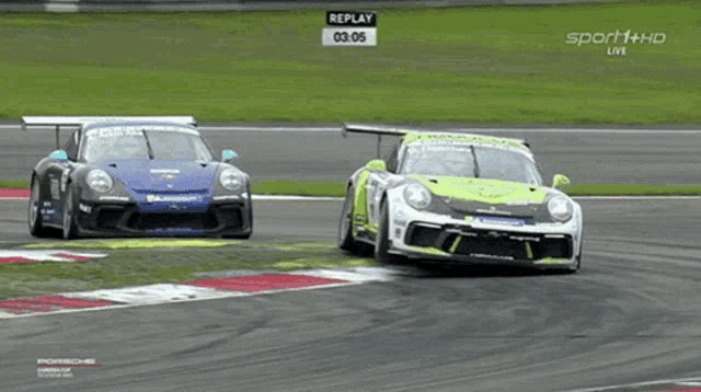 two race cars are racing on a track with a replay sign above them