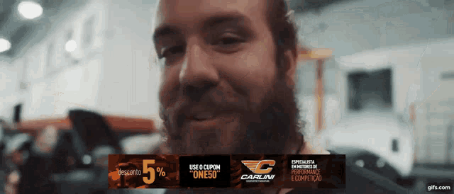 a man with a beard is smiling in front of a banner that says carlini