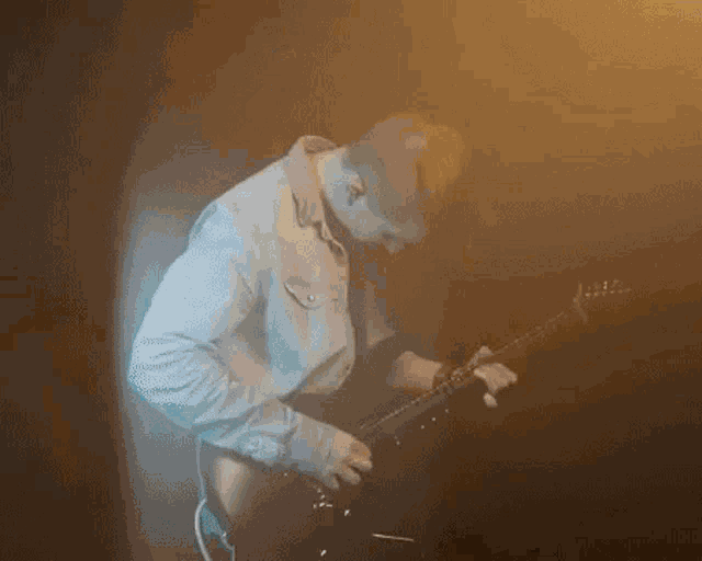 a man in a denim shirt is playing a guitar in a dark room .