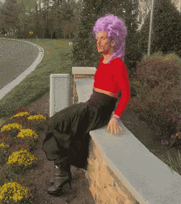 a woman with purple hair sits on a wall