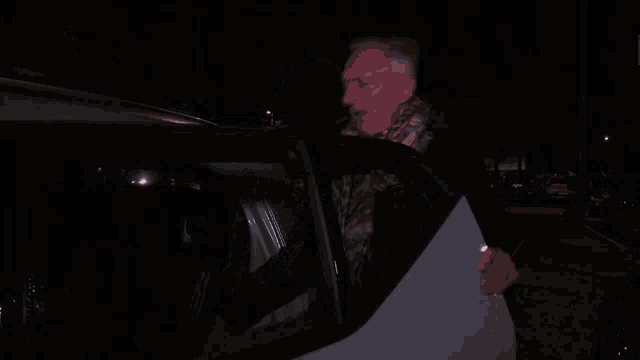 a man is sitting in the back seat of a police car at night