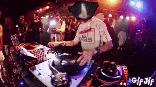 a dj is playing music in front of a crowd at a party while wearing a mask .