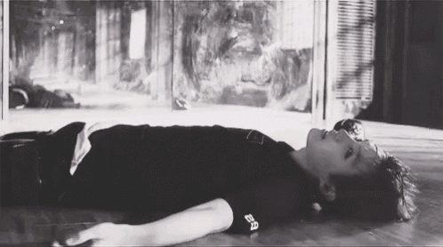 a black and white photo of a person laying on the floor with their head on the floor .