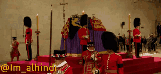 a group of men in red uniforms standing in front of a purple coffin