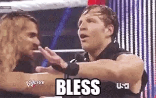 two wrestlers are giving each other a high five and the word bless is on the screen behind them .