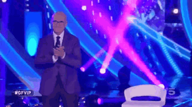 a man in a suit and tie stands in front of a stage with the hashtag #gfvip on it