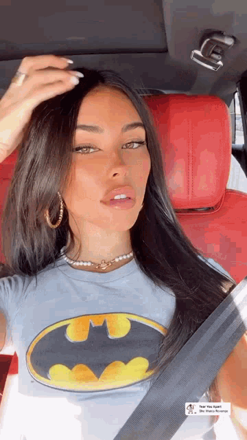 a woman wearing a batman t-shirt is sitting in a car .