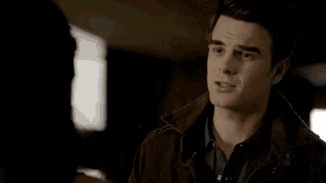 a man in a brown jacket is talking to a woman .
