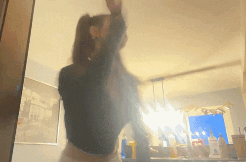 a blurry picture of a woman dancing in a room with a picture of a city on the wall