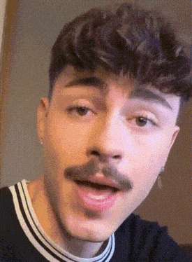 a young man with a mustache is making a funny face .