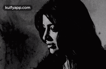 a black and white photo of a woman 's face with a shadow on the wall .