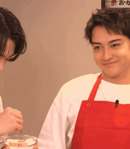 a man in a red apron looks at another man