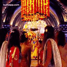 a group of women in traditional indian clothing are walking through a hallway .