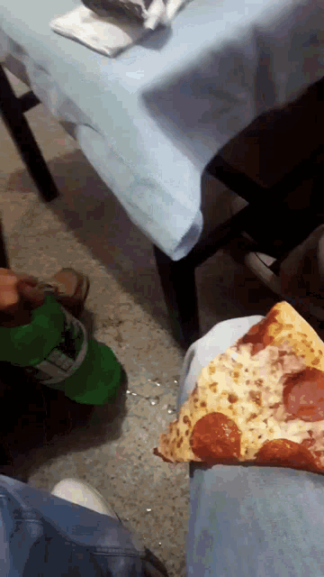 a person is eating a slice of pepperoni pizza next to a bottle of sprite