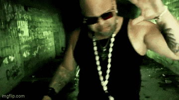a man wearing sunglasses and a necklace is standing in front of a green wall .
