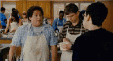 a group of people are standing in a kitchen wearing aprons .