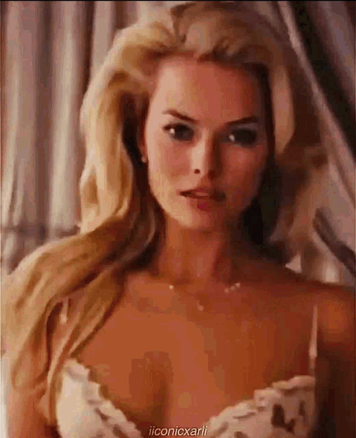 a woman with long blonde hair is wearing a white bra and necklace .