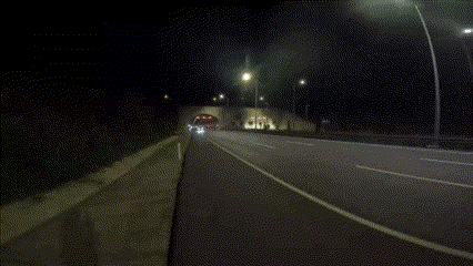 a car is driving down a highway at night near a tunnel