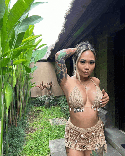 a woman in a bikini is standing in a garden